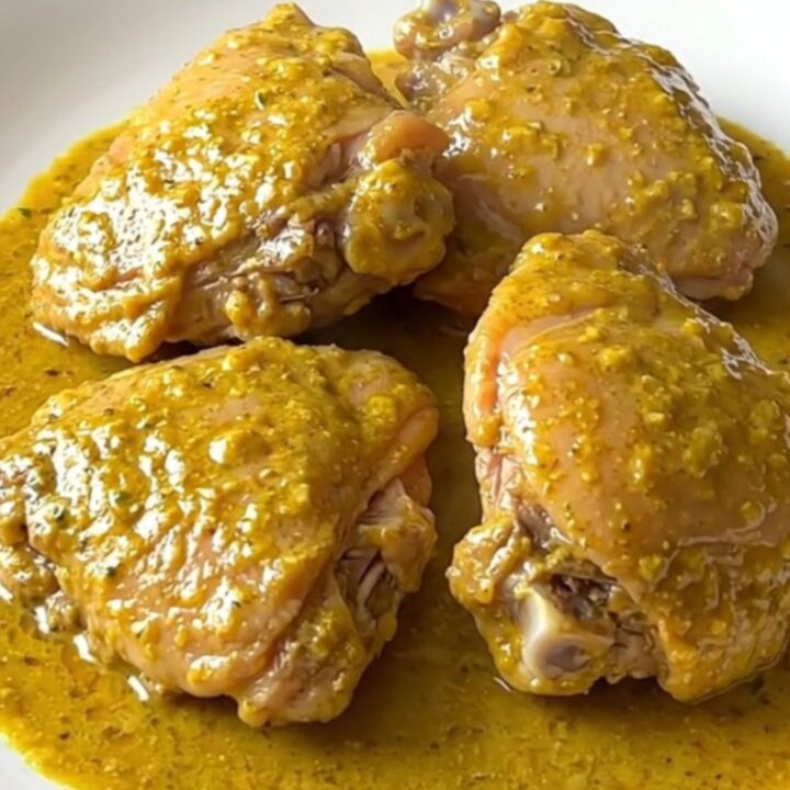 A high-angle shot of raw turkey thighs and cubed sweet potatoes in a slow cooker crock with coconut milk.