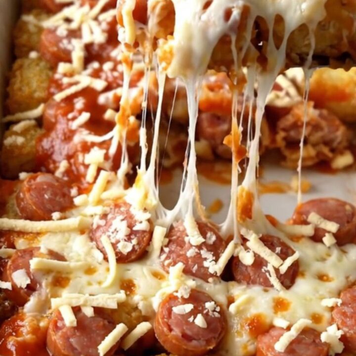 A rectangular baking dish filled with a golden, bubbling cheesy potato tot and sausage bake.