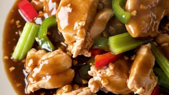 A high-angle shot of tender chicken chunks in a savory garlic sauce with colorful bell peppers and celery.