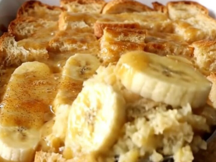 A top-down view of a rectangular baking dish filled with golden-brown bread pudding and soft banana slices.