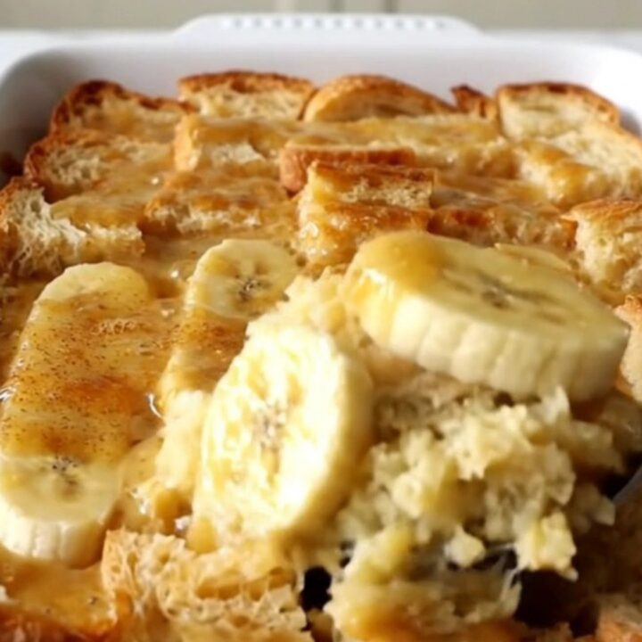 A top-down view of a rectangular baking dish filled with golden-brown bread pudding and soft banana slices.