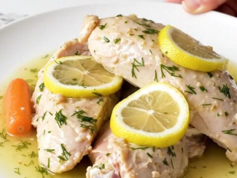 A plate of cooked, tender turkey breast tenderloins with baby carrots and a lemon dill sauce.