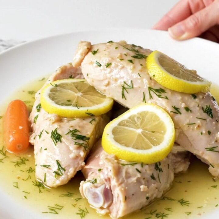 A plate of cooked, tender turkey breast tenderloins with baby carrots and a lemon dill sauce.