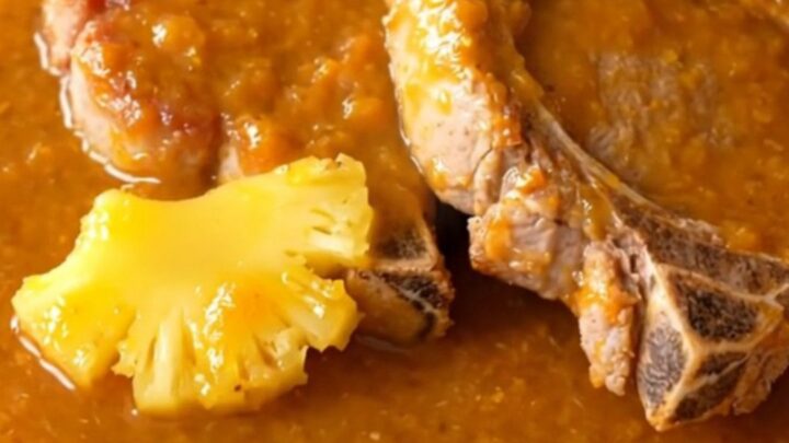 Five succulent, braised pork chops coated in a glossy orange pineapple habanero sauce on a white plate.