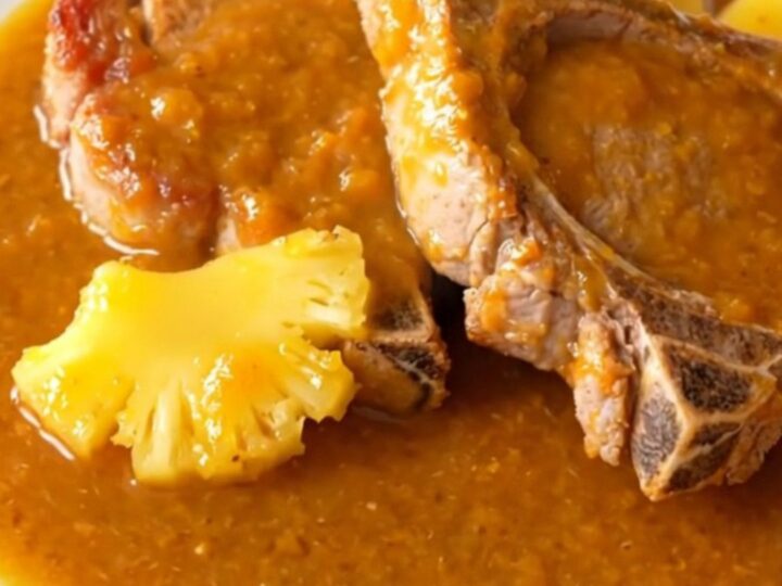 Five succulent, braised pork chops coated in a glossy orange pineapple habanero sauce on a white plate.