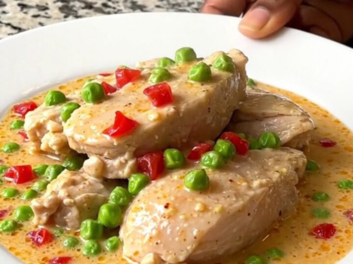 A close-up view of creamy Chicken a la King in a slow cooker, featuring chicken chunks, peas, and pimentos.