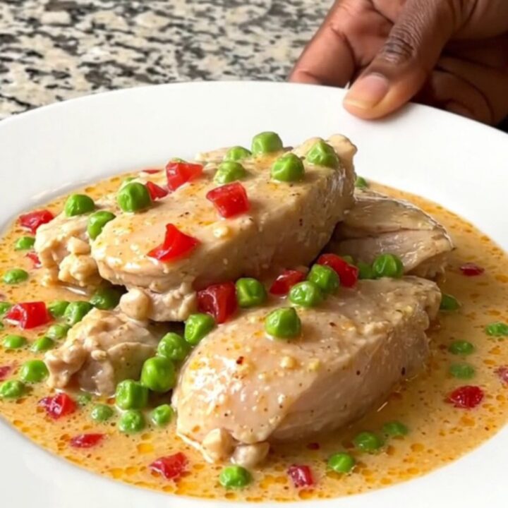 A close-up view of creamy Chicken a la King in a slow cooker, featuring chicken chunks, peas, and pimentos.