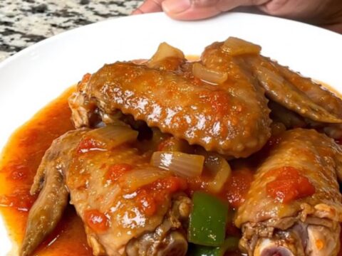 A close-up of tender, slow-cooked turkey wings in a rich tomato gravy served on a white plate.