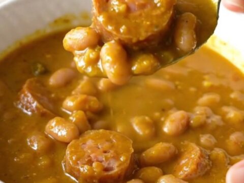 A slow cooker filled with pumpkin sausage stew featuring Italian sausage rounds and white beans.