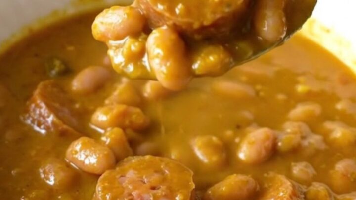 A slow cooker filled with pumpkin sausage stew featuring Italian sausage rounds and white beans.