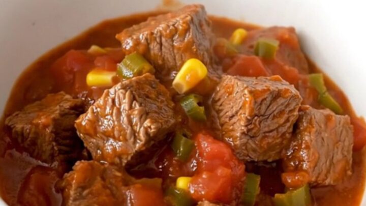 A close-up of tender beef tips, black beans, and corn in a rich tomato sauce inside a slow cooker.