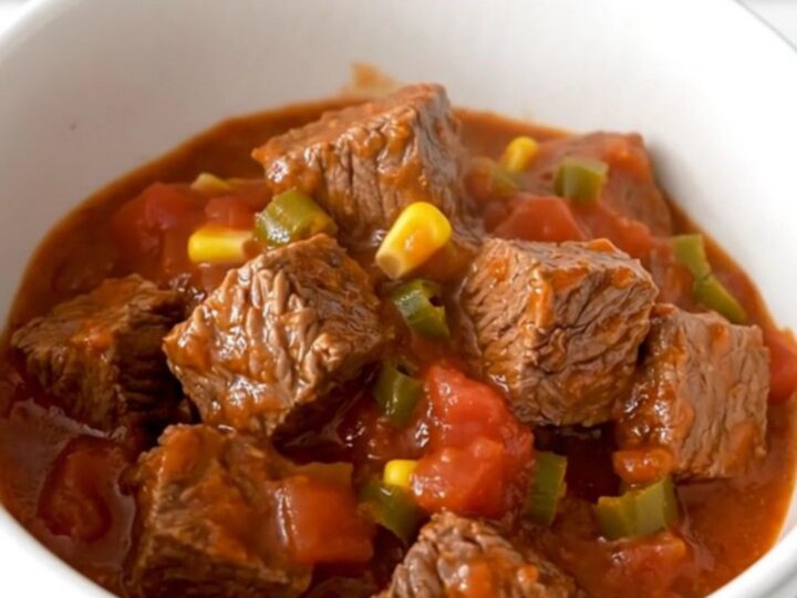 A close-up of tender beef tips, black beans, and corn in a rich tomato sauce inside a slow cooker.