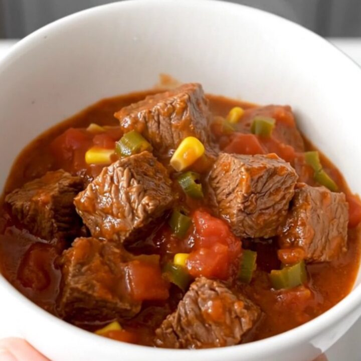 A close-up of tender beef tips, black beans, and corn in a rich tomato sauce inside a slow cooker.
