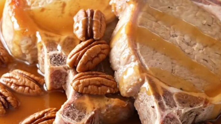 A close-up of tender boneless pork chops glazed in a rich maple butter sauce with scattered pecans in a slow cooker.