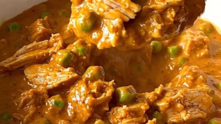 A top-down view of a slow cooker filled with ground turkey, peas, and creamy tikka masala sauce.