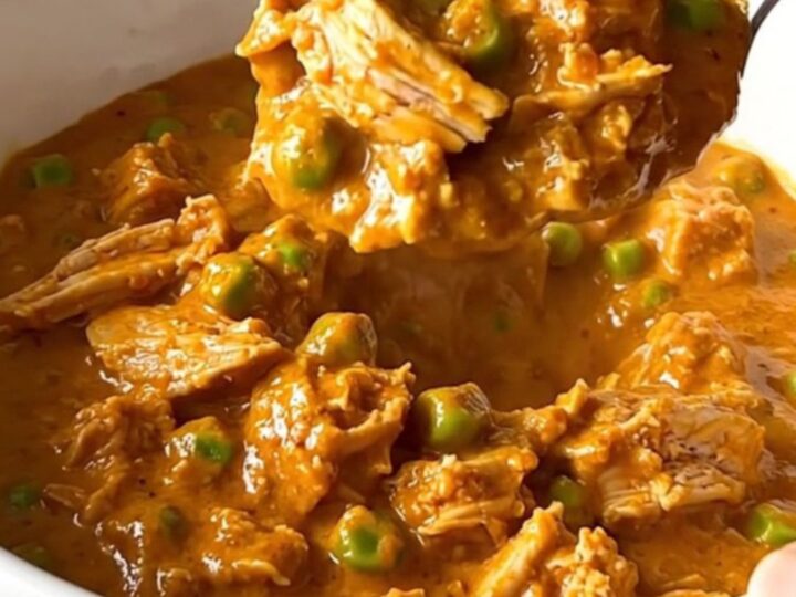 A top-down view of a slow cooker filled with ground turkey, peas, and creamy tikka masala sauce.