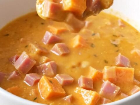 A rustic bowl of creamy maple ham and sweet potato chowder with visible chunks of ham and soft potatoes.