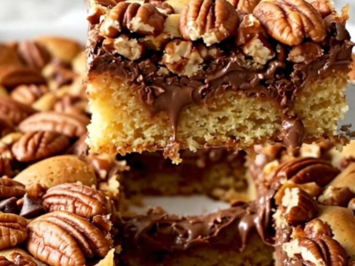 A top-down view of chocolate chip pecan pie bars in a ceramic dish on a speckled countertop.
