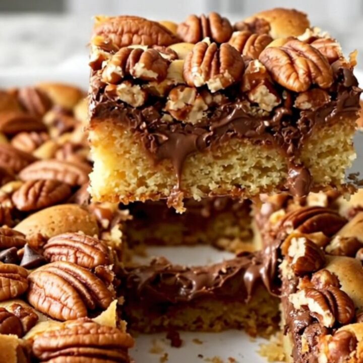 A top-down view of chocolate chip pecan pie bars in a ceramic dish on a speckled countertop.