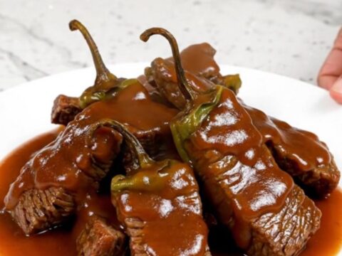 A bowl of Crockpot Sriracha Honey Beef Tips with peppers and a thick glaze.