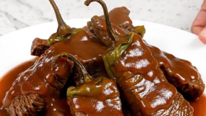 A bowl of Crockpot Sriracha Honey Beef Tips with peppers and a thick glaze.