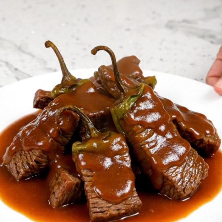 A bowl of Crockpot Sriracha Honey Beef Tips with peppers and a thick glaze.
