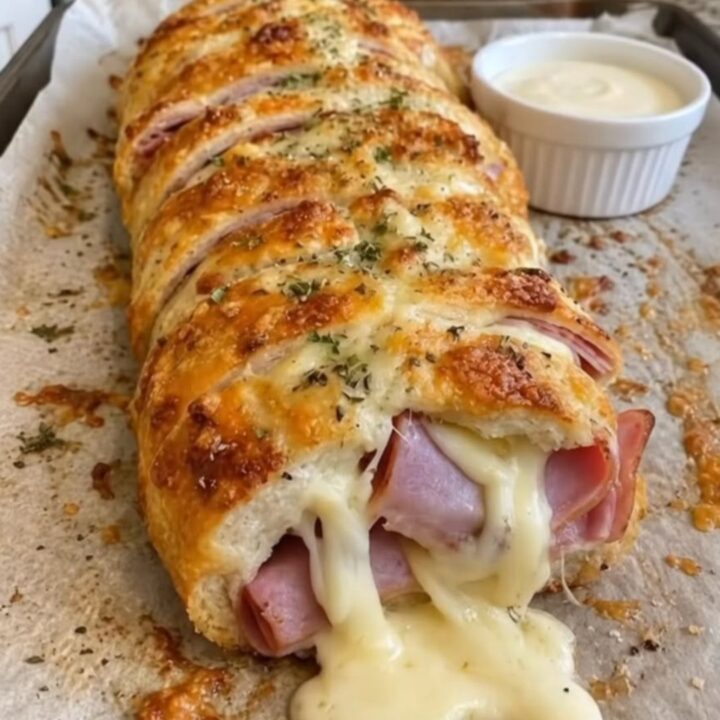 A golden-brown pull-apart bread loaf with melted cheese and ham visible in the crevices.