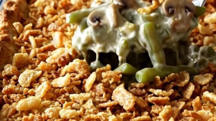 A top-down view of a rectangular white baking dish filled with raw green beans, creamy mushroom sauce, and crispy onions.
