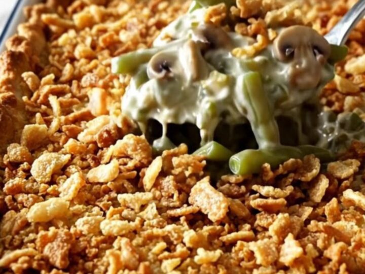 A top-down view of a rectangular white baking dish filled with raw green beans, creamy mushroom sauce, and crispy onions.