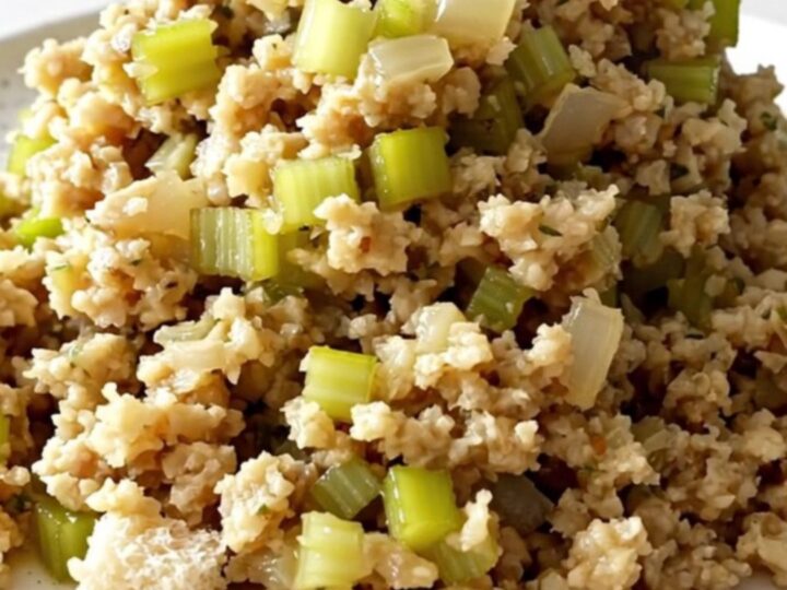 A top-down view of a slow cooker filled with bread cubes, diced celery, and onions, ready to be cooked.