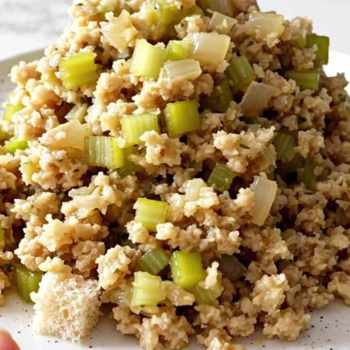 A top-down view of a slow cooker filled with bread cubes, diced celery, and onions, ready to be cooked.