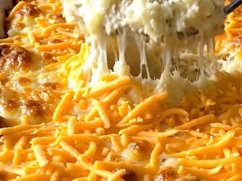 A creamy million dollar mashed potato casserole in a white dish, topped with golden melted cheddar and garlic butter.