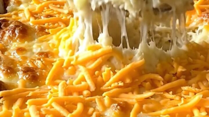 A creamy million dollar mashed potato casserole in a white dish, topped with golden melted cheddar and garlic butter.