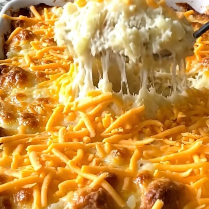 A creamy million dollar mashed potato casserole in a white dish, topped with golden melted cheddar and garlic butter.