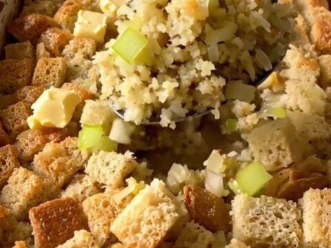 A golden-brown herb butter stuffing bake in a white rectangular baker on a granite countertop.