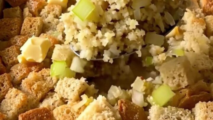 A golden-brown herb butter stuffing bake in a white rectangular baker on a granite countertop.
