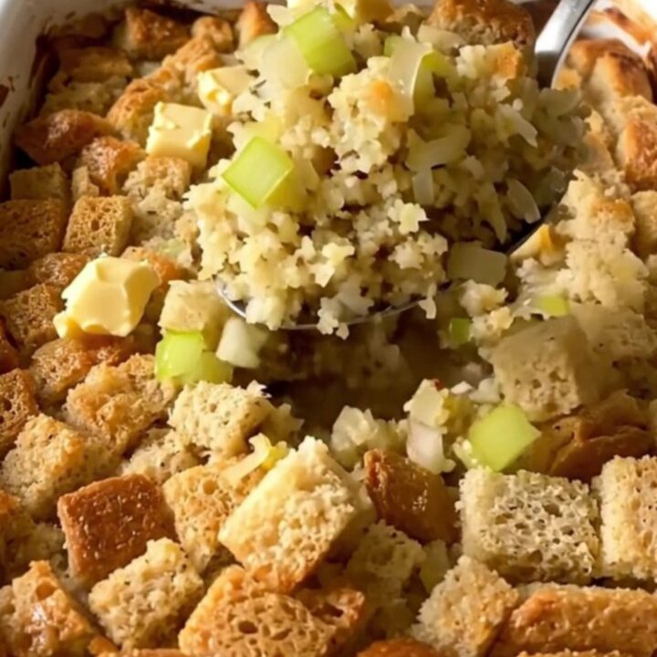 A golden-brown herb butter stuffing bake in a white rectangular baker on a granite countertop.