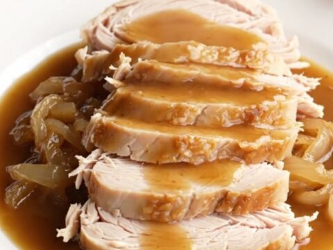 A succulent boneless turkey breast cooked in a slow cooker with rich brown gravy and onions.