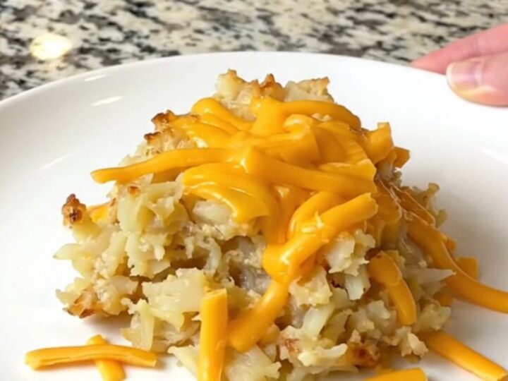 A close-up of creamy, cheesy hash brown potatoes in a black slow cooker bowl.