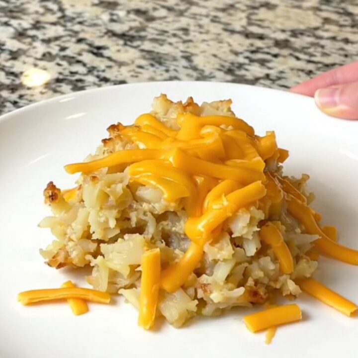 A close-up of creamy, cheesy hash brown potatoes in a black slow cooker bowl.