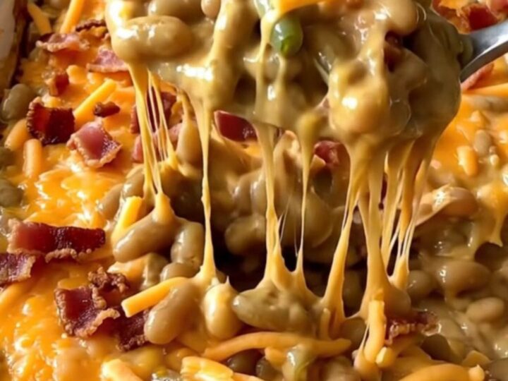A top-down view of a rectangular baking dish filled with green beans, creamy cheddar sauce, bacon, and cheese.