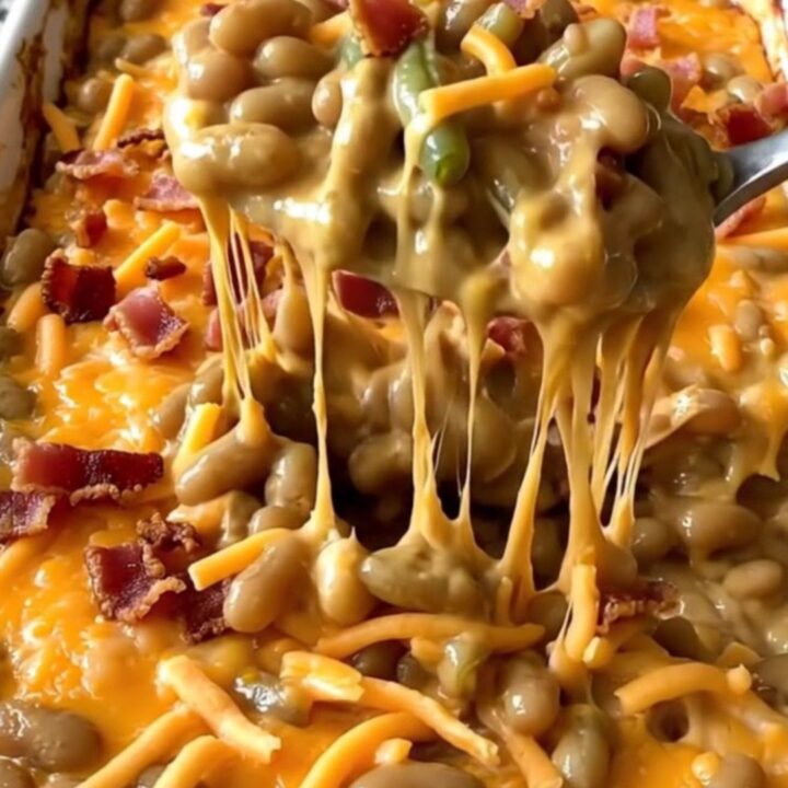 A top-down view of a rectangular baking dish filled with green beans, creamy cheddar sauce, bacon, and cheese.