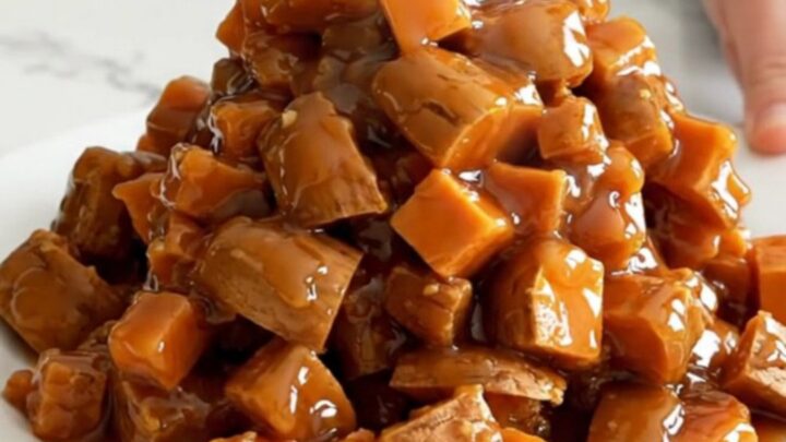 A close-up of tender, caramelized sweet potato cubes in a dark slow cooker, covered in a glossy