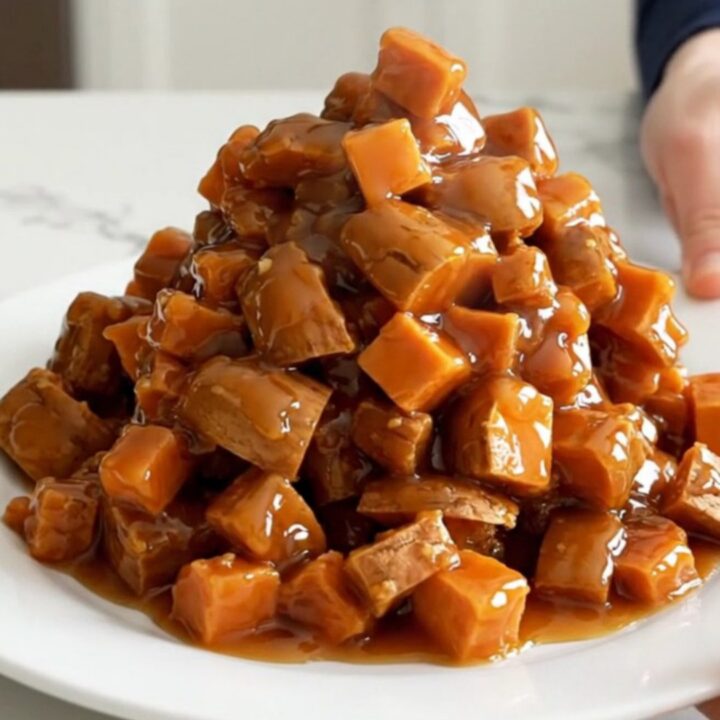 A close-up of tender, caramelized sweet potato cubes in a dark slow cooker, covered in a glossy