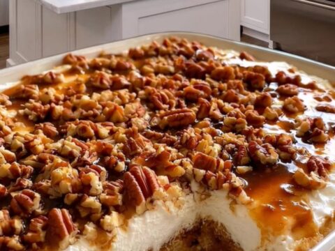 A slice of decadent pecan caramel poke cake on a plate showing layers of cake, caramel, and whipped cream.