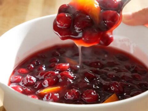 A vibrant, jammy cranberry orange sauce in a white ceramic slow cooker