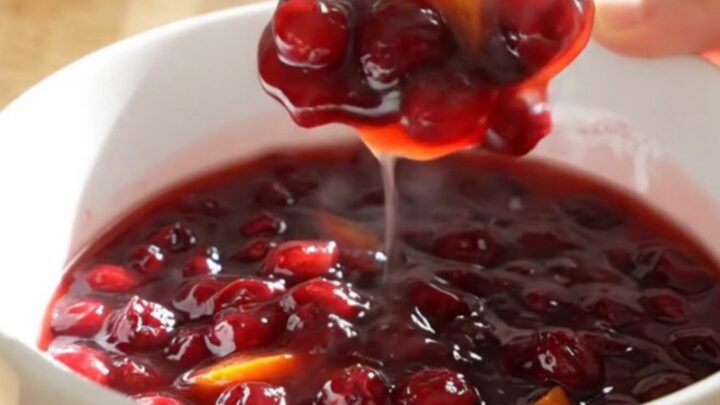 A vibrant, jammy cranberry orange sauce in a white ceramic slow cooker