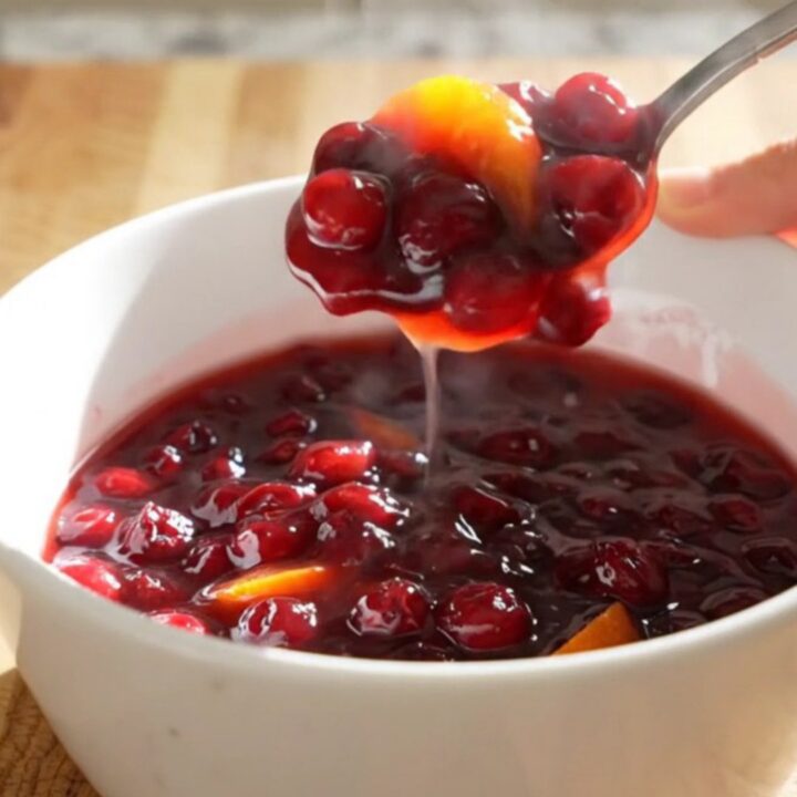 A vibrant, jammy cranberry orange sauce in a white ceramic slow cooker