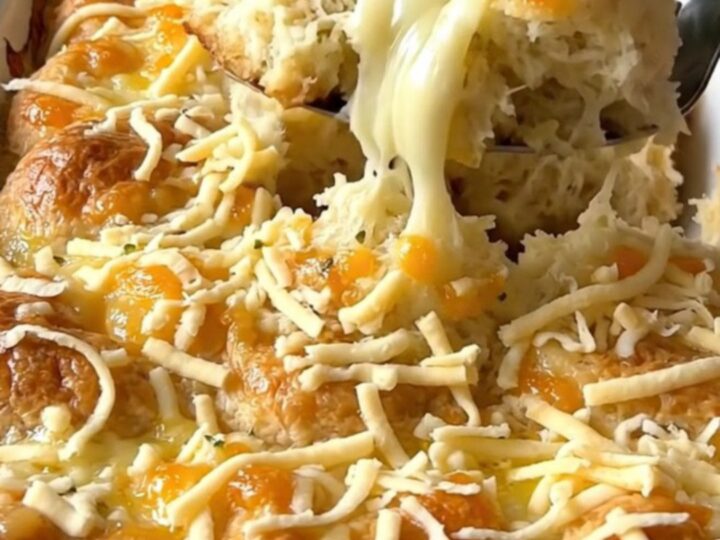 A top-down view of quartered biscuit dough pieces in a rectangular white baker, drizzled with garlic butter.