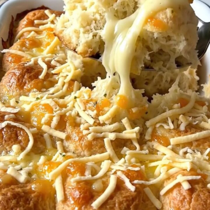 A top-down view of quartered biscuit dough pieces in a rectangular white baker, drizzled with garlic butter.